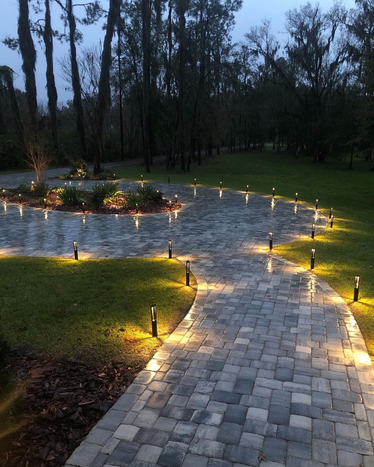 Pathway lights glowing along a paver walkway at night